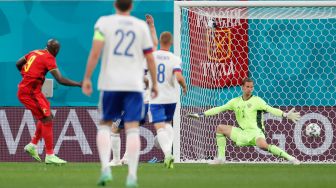 Pemain depan Belgia Romelu Lukaku (kiri) mencetak gol pertama timnya melewati kiper Rusia Anton Shunin (kanan) selama pertandingan sepak bola Grup B EURO 2020 antara Belgia melawan Rusia di Stadion Saint Petersburg di Saint Petersburg, Rusia, Minggu (13/6). dinih hari WIB.  Anatoly Maltsev / POOL / AFP