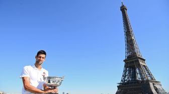 Petenis tunggal putera Serbia Novak Djokovic berpose dengan piala kemenangannya di depan Menara Eiffel, di Paris, Prancis, Senin (14/6 /2021).  Christophe ARCHAMBAULT / POOL / AFP