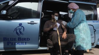 Vaksinator menyuntikkan vaksin COVID-19 kepada penyandang disabilitas di Pool Bluebird Kramat Jati, Jakarta, Senin (14/6/2021). [Suara.com/Angga Budhiyanto]