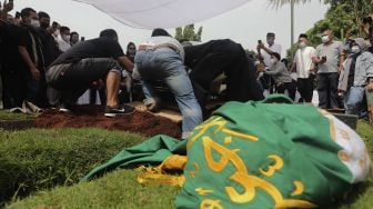 Keluarga menguburkan jenazah legenda bulutangkis Indonesia, Markis Kido di TPU Kebon Nanas, Cipinang, Jakarta, Selasa (15/6/2021). [Suara.com/Angga Budhiyanto]