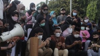 Keluarga dan kerabat memanjatkan doa saat prosesi penguburan jenazah legenda bulutangkis Indonesia, Markis Kido di TPU Kebon Nanas, Cipinang, Jakarta, Selasa (15/6/2021). [Suara.com/Angga Budhiyanto]