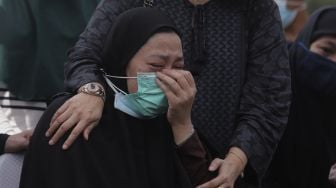 Ekspresi anggota keluarga saat penguburan jenazah legenda bulutangkis Indonesia, Markis Kido di TPU Kebon Nanas, Cipinang, Jakarta, Selasa (15/6/2021). [Suara.com/Angga Budhiyanto]