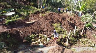 Warga melintasi area longsor di Pakel, Licin, Banyuwangi, Jawa Timur, Kamis(17/6/2021). ANTARA FOTO/Budi Candra Setya