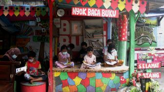 Sejumlah anak membaca buku di Bale Buku, Gang Dendrit, Cakung, Jakarta Timur, Jumat (18/6/2021).[Suara.com/Dian Latifah]