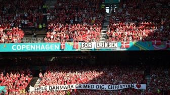 Suporter Denmark membentangkan spanduk dukungan untuk Christian Eriksen saat laga Piala Eropa 2020 Grup B antara Denmark melawan Belgia di Parken Stadium, Copenhagen, Kamis (17/6/2021).  [AFP/Photo]