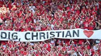 Suporter Denmark membentangkan spanduk dukungan untuk Christian Eriksen saat laga Piala Eropa 2020 Grup B antara Denmark melawan Belgia di Parken Stadium, Copenhagen, Kamis (17/6/2021).  [AFP/Photo]