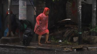 Warga beraktivitas dengan mengenakan jas hujan saat hujan deras di kawasan Pinang Ranti, Jakarta Timur, Jumat (18/6/2021). [Suara.com/Alfian Winanto]
