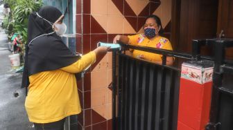 Warga membagikan masker ke warga lainnya di Kampung Tangguh Jaya RW 13 Bidara Cina, Jakarta Timur, Sabtu (19/6/2021). [Suara.com/Alfian Winanto]