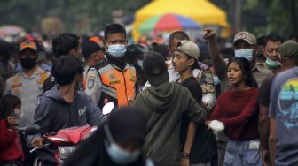 Petugas memberi imbauan kepada sejumlah warga yang memadati kawasan Hutan Kota untuk menerapkan protokol kesehatan di Bekasi, Jawa Barat, Minggu (20/6/2021). [Suara.com/Dian Latifah] 