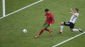 Pemain depan Portugal Cristiano Ronaldo (kiri) mencetak gol pertama mereka selama pertandingan sepak bola Grup F UEFA EURO 2020 antara Portugal dan Jerman di Allianz Arena, Munich pada (19/6/2021). [Matthias Hangst / POOL / AFP]