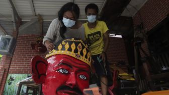 Seniman menyelesaikan pembuatan ondel-ondel Betawi ukuran besar di kawasan Jagakarsa, Jakarta Selatan, Senin (21/6/2021). [Suara.com/Angga Budhiyanto]