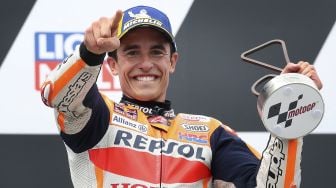 Pembalap Honda Spanyol Marc Marquez merayakan dengan trofi setelah memenangkan Grand Prix MotoGP Jerman di sirkuit balap Sachsenring, Hohenstein-Ernstthal, Jerman Timur, pada (20/6/2021). [Ronny HARTMANN / AFP]