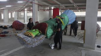 Sejumlah pekerja menggotong ondel-ondel Betawi raksasa yang akan dipasang di Taman Ismail Marzuki (TIM), Jakarta, Selasa (22/6/2021). [Suara.com/Angga Budhiyanto]