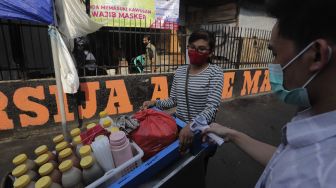 Warga memeriksa suhu tubuh pedagang yang melintas di zona merah COVID-19 RT 006 RW 01, Gandaria Selatan, Cilandak, Jakarta, Selasa (22/6/2021). [Suara.com/Angga Budhiyanto]