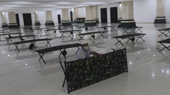 Petugas menyiapkan tempat tidur bagi warga yang akan menjalani isolasi mandiri di Masjid Raya KH Hasyim Asy'ari, Jakarta, Rabu (23/6/2021). [Suara.com/Angga Budhiyanto]