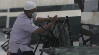 Petugas menyiapkan tempat tidur bagi warga yang akan menjalani isolasi mandiri di Masjid Raya KH Hasyim Asy'ari, Jakarta, Rabu (23/6/2021). [Suara.com/Angga Budhiyanto]