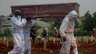 Petugas mengangkat peti jenazah pasien Covid-19 di TPU Padurenan, Mustika Jaya, Bekasi, Rabu (23/6/2021).  [Suara.com/Dian Latifah]
