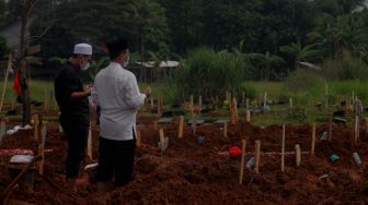 Keluarga berdoa di makam jenazah pasien covid-19 di TPU Padurenan, Mustika Jaya, Bekasi, Rabu (23/6/2021). [Suara.com/Dian Latifah]   