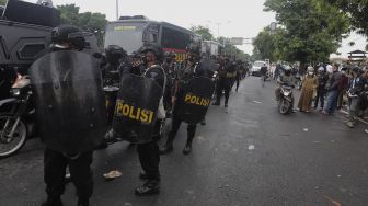 Aparat kepolisian bersiaga saat sejumlah massa pendukung Rizieq Shihab memblokade jalan di kawasan I Gusti Ngurah Rai, Jakarta, Kamis (24/6/2021). [Suara.com/Angga Budhiyanto]