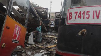 Seorang warga beraktivitas di dekat potongan bus Transjakarta di Terminal Pulogadung, Jakarta, Kamis (24/6/2021). [Suara.com/Angga Budhiyanto]