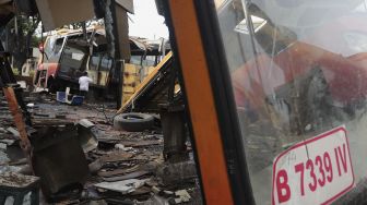 Seorang warga beraktivitas di dekat potongan bus Transjakarta di Terminal Pulogadung, Jakarta, Kamis (24/6/2021). [Suara.com/Angga Budhiyanto]