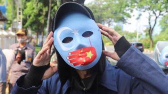 Massa koalisi Indonesia Save Uyghur menggunakan topeng saat aksi damai di depan gedung Kemenpora, Jakarta Pusat, Jumat (25/6/2021). [Suara.com/Alfian Winanto]