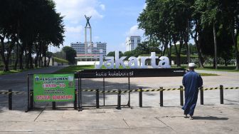 Warga melintas di dekat Taman Lapangan Banteng yang ditutup untuk sementara waktu di Jakarta, Jumat (25/6/2021).  ANTARA FOTO/Akbar Nugroho Gumay
