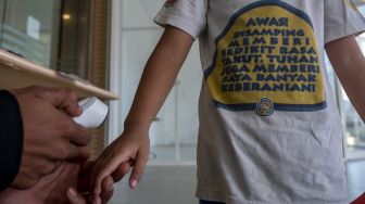 Petugas memeriksa suhu tubuh seorang anak sebelum memasuki kawasan perbelanjaan di Palu, Sulawesi Tengah, Kamis (24/6/2021). ANTARAFOTO/Basri Marzuki
