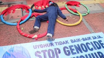 Massa koalisi Indonesia Save Uyghur melakukan pertunjukan teatrikal saat aksi damai di depan gedung Kemenpora, Jakarta Pusat, Jumat (25/6/2021). [Suara.com/Alfian Winanto]