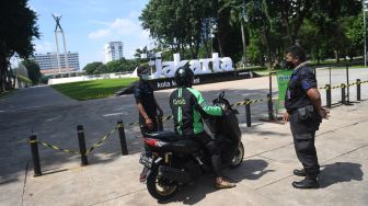 Petugas gabungan memberikan penjelasan soal ditutupnya Taman Lapangan Banteng untuk sementara kepada pengendara motor di Jakarta, Jumat (25/6/2021). ANTARA FOTO/Akbar Nugroho Gumay
