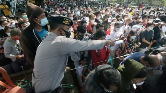 Anggota Polisi mengarahkan ribuan warga yang antre vaksinasi COVID-19 massal di Denpasar, Bali, Sabtu (26/6/2021).FOTO/Nyoman Hendra Wibowo