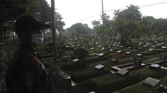 Petugas keamanan berjaga di Tempat Pemakaman Umum (TPU) Karet Bivak, Jakarta, Minggu (27/6/2021). [Suara.com/Angga Budhiyanto]