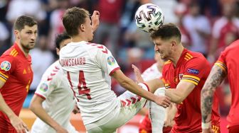 Bek Wales Chris Mepham berebut bola dengan pemain depan Denmark Mikkel Damsgaard selama pertandingan sepak bola babak 16 besar UEFA EURO 2020 antara Wales dan Denmark di Johan Cruyff Arena, Amsterdam, pada (26/6/2021). [Olaf Kraak / POOL / AFP]