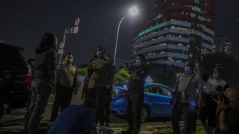 Petugas keamanan menghentikan aksi aktivis Greenpeace saat menggelar aksi dengan menembakan sinar laser yang bertuliskan #mositidakpercaya di Gedung Merah Putih KPK, Jakarta, Senin (28/6/2021). [ANTARA FOTO/Galih Pradipta]