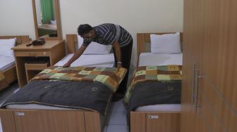 Petugas mempersiapkan kamar yang akan dipakai untuk tempat isolasi mandiri di Asrama Haji Pondok Gede, Jakarta Timur, Selasa (29/6/2021). [Suara.com/Alfian Winanto]