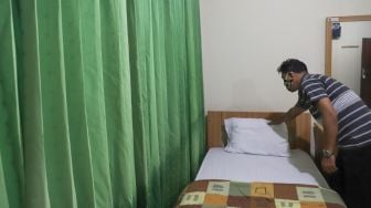 Petugas mempersiapkan kamar yang akan dipakai untuk tempat isolasi mandiri di Asrama Haji Pondok Gede, Jakarta Timur, Selasa (29/6/2021). [Suara.com/Alfian Winanto]