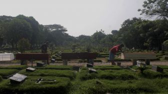 Pekerja menyelesaikan pembuatan peti mati di Yayasan Sahabat Duka, TPU Pondok Kelapa, Jakarta, Selasa (29/6/2021). [Suara.com/Dian Latifah]