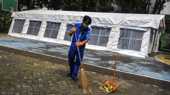 Karyawan Rumah Sakit Umum Daerah (RSUD) Tarakan membersihkan sampah di samping tenda darurat yang didirikan di halaman SDN 2 Cideng, Jakarta, Selasa (29/6/2021). [ANTARA FOTO/M Risyal Hidayat]