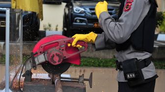 Petugas kepolisian memotong sepucuk senjata api laras panjang rakitan saat rilis pemusnahannya di Mapolda Jambi, Jambi, Rabu (30/6/2021). ANTARA FOTO/Wahdi Septiawan