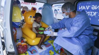 Tenaga medis memberikan mainan kepada seorang anak sebelum mengambil sampel swab di dalam sebuah mobil van yang dihiasi dengan mainan di New Delhi, India, pada (1/7/2021). [Prakash SINGH / AFP]