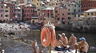 Warga duduk dan mengobrol di desa tepi laut tua Boccadasse, Genoa, pada (28/6/2021). [MARCO BERTORELLO / AFP]