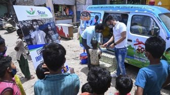 Relawan memberikan makanan ringan kepada seorang anak laki-laki setelah memberikan sampel swab di New Delhi, India, pada (1/7/2021). [Prakash SINGH / AFP]