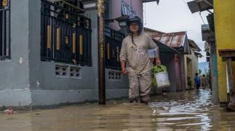 Warga berjalan di pemukiman yang digenangi air akibat sungai meluap di Kelurahan Baru, Palu, Sulawesi Tengah, Sabtu (3/7/2021). [ANTARA FOTO/Basri Marzuki]