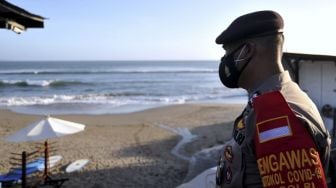 Polisi melakukan pengawasan Pemberlakuan Pembatasan Kegiatan Masyarakat (PPKM) Darurat di objek wisata pantai yang ditutup di kawasan Canggu, Badung, Bali, Minggu (4/7/2021). [ANTARA FOTO/Fikri Yusuf]