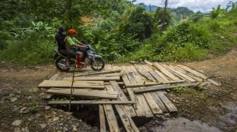 Pengendara motor melintasi jembatan yang rusak di Desa Hinas Kanan, Kabupaten Hulu Sungai Tengah, Kalimantan Selatan, Minggu (4/7/2021). [ANTARA FOTO/Bayu Pratama S]