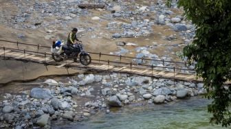 Pengendara melintas di jembatan yang rusak di Desa Datar Ajab, Kabupaten Hulu Sungai Tengah, Kalimantan Selatan, Minggu (4/7/2021). [ANTARA FOTO/Bayu Pratama S]