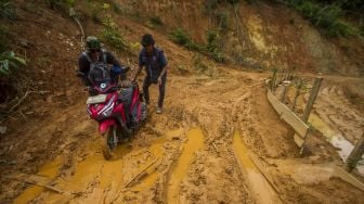 Warga mendorong motornya akibat kesulitan melintasi jalan yang rusak tertutup lumpur tanah longsor di Desa Hinas Kanan, Kabupaten Hulu Sungai Tengah, Kalimantan Selatan, Minggu (4/7/2021). [ANTARA FOTO/Bayu Pratama S]