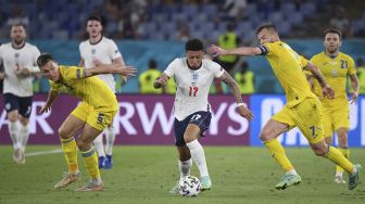 Pemain depan Inggris Jadon Sancho (tengah) dijaga oleh pemain depan Ukraina Andriy Yarmolenko (kanan) dan pemain tengah Ukraina Serhiy Sydorchuk (kiri) selama pertandingan sepak bola perempat final UEFA EURO 2020 antara Ukraina dan Inggris di Stadion Olimpiade, Roma, pada (3/7/2021). [ALBERTO LINGRIA / POOL / AFP]