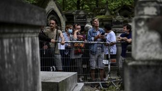 Orang-orang berkumpul di dekat makam pentolan The Doors Jim Morrison untuk memperingati 50 tahun kematiannya di pemakaman Pere Lachaise, Paris, pada (3/7/2021). [Martin BUREAU / AFP]