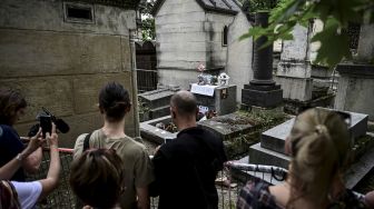 Orang-orang berkumpul di dekat makam pentolan The Doors Jim Morrison untuk memperingati 50 tahun kematiannya di pemakaman Pere Lachaise, Paris, pada (3/7/2021). [Martin BUREAU / AFP]